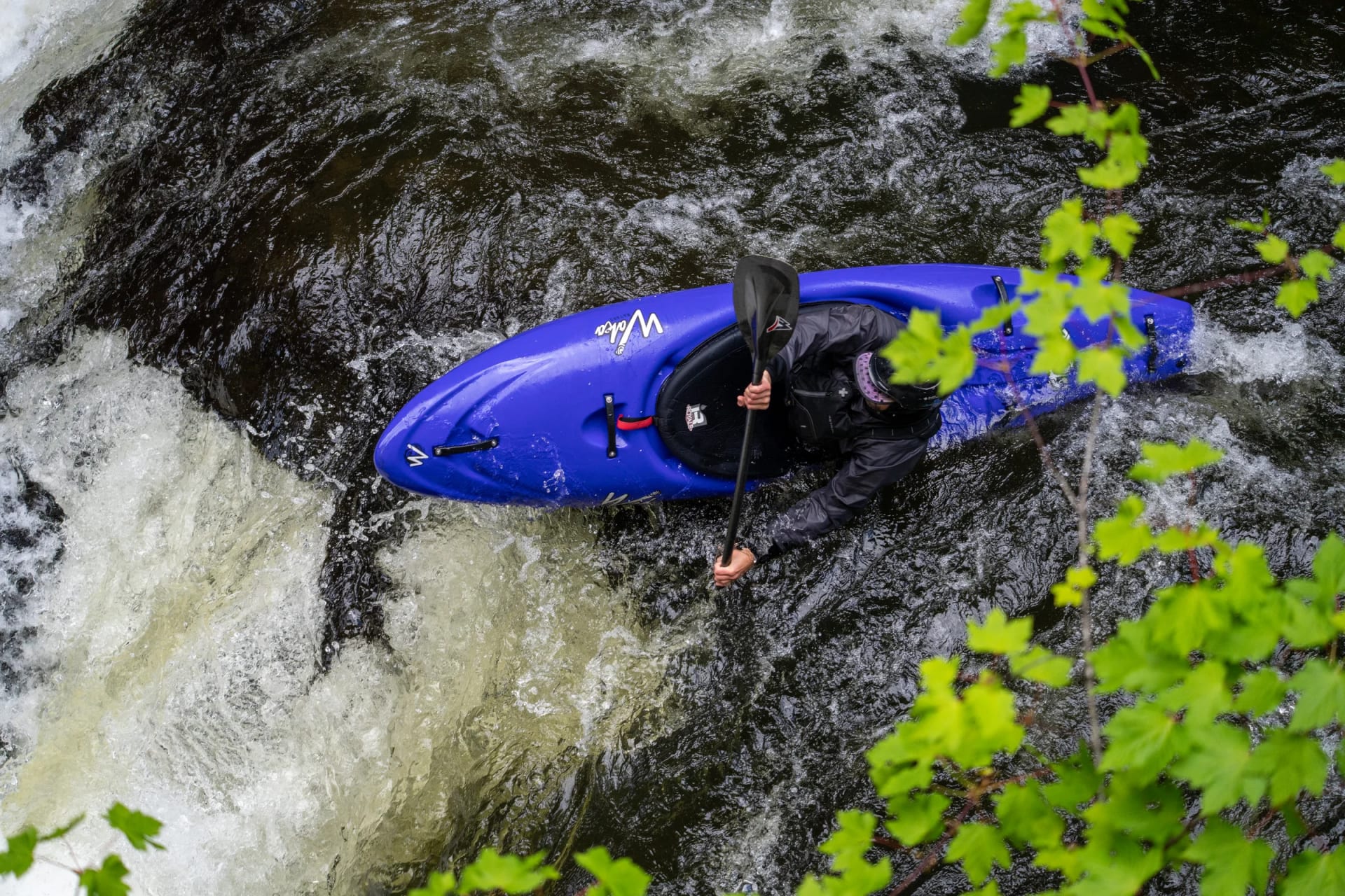 Whitewater kayaker navigating rapids through a mountain canyon